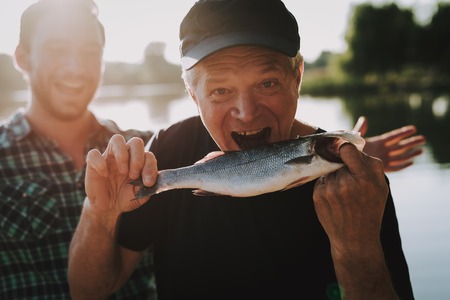Old Father with Bearded Son Fishing on River in Summer. Relaxing Outdoor. Bearded Young Man. Men...
