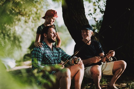Young Man with Son and Father Fishing on River in Summer. Relaxing Outdoor. Old Man and Boy. Men...