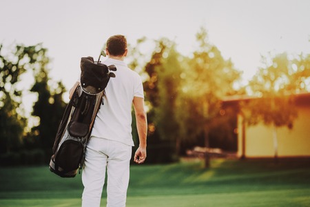 Young Man in White Clothes Playing Golf on Field. Relaxing in Golf Club. Sports in Summer. Outdoor Fun in Summer. Happy Young Man. Healthy Lifestyle Concept. Man it White Shirt. Green Grass.の写真素材