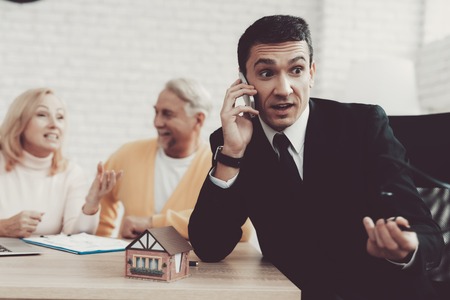 Man and Woman Consulting with Realtor in Office. Important Documents. Real Estate Conceps. Grandfather and Grandmother. People with Gray Hair. Young Realtor in Suit. House for Rent.の写真素材