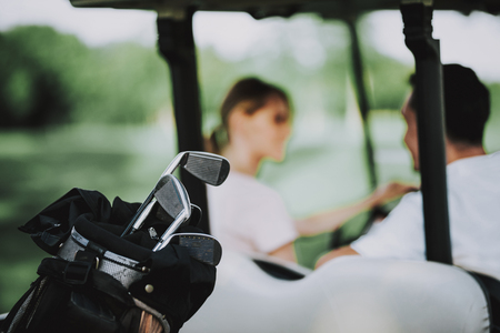 Happy Young Couple in White Cart on Golf Field. Young Family. Golf Club. Sports in Summer. Vehicle on Field. Outdoor Fun in Summer. Driver with Car. Healthy Lifestyle Concept. Couple on Vacation.の写真素材