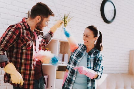 Young Couple in Checkered Shirts Cleaning Room. Sanitary at Home. Hands in Rubber Gloves....