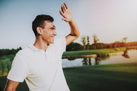 Young Man in White Clothes Playing Golf on Field. Relaxing in Golf Club. Sports in Summer. Outdoor Fun in Summer. Happy Young Man. Healthy Lifestyle Concept. Man it White Shirt. Green Grass.の写真素材
