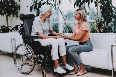 Patient Undergoes Rehabilitation. After Treatment for Cancer. Cancer Patient on a Wheelchair. A Woman with Daughter. Woman Glad See Daughter. Recovering Woman. Remission. Clinic. Cancer Patient.の写真素材