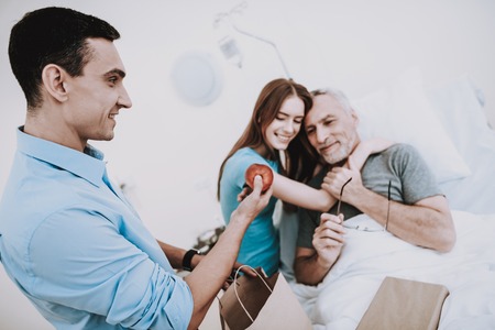 Man and Young Girl in Hospital and Happy Man. Young Man in Hospital with Young Girl. Health Girl and Young Man in Clinic. Food for Old Man and Good Health. Care for Old Patient. White Room for Man.の写真素材