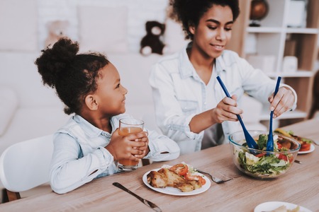 Young Girl with Mother Time Together. Love Mom and Beautiful Girl. Mulatto Mother and Mulatto Girl Time Together. People Relaxation and Eat Food. Smile Little Girl and Young Mother. Beautiful Girl.の写真素材