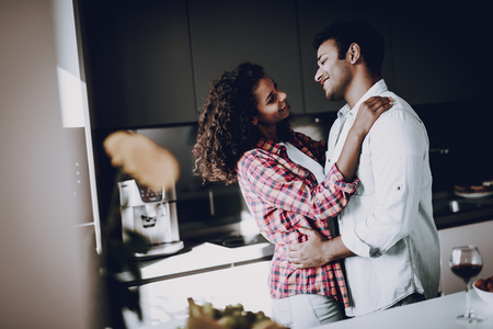 Afro American Couple Is Hanging In Kitchen. Weekend Concept. Holiday Resting. Smiling Together. Having Fun. Romantic Date. Cheerful Sweethearts. Staring At Each Other. Happy Family.の写真素材