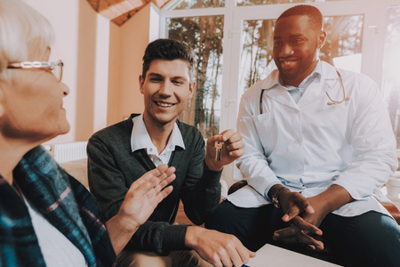 Family Relationships. Bequeaths House. Keys. Signs Contract. Happy Together.Black Doctor. Testament. Nursing Home. Retired Person. Sunshine Day. Sitting People. Elderly Woman. Young Man.の写真素材