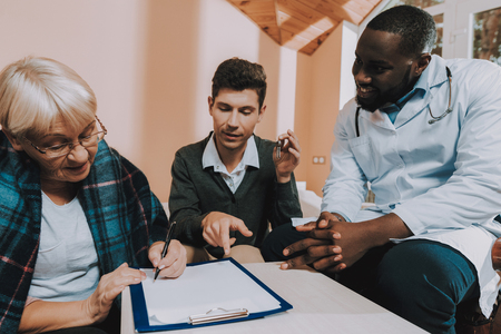 Happy Together. Bequeaths House. Keys. Signs Contract. Black Doctor. Testament. Nursing Home. Retired Person. Family Relationships. Sunshine Day. Sitting People. Elderly Woman. Young Man.の写真素材