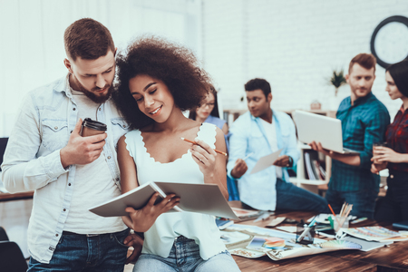 Examine Documents. Mulatto Girl. White Man. Man and Woman. Project. Teamwork. Brainstorm. Working Desks. Large Bright Office. Cooperation. Different Nationalities. Work. Table. Design. Company.の写真素材