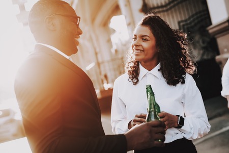 Smile. Alcoholic Beverage. Man and Woman. Stand. Street. Bottles. Sun Shines Brightly. Adventure. Afro. Lifestyle. Cheerful. Drink. Stylish. Alcohol. Young. Emotion. Enjoy. Sunset. Spring. Curly.の写真素材