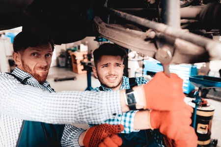 Young Mechanic Repairs Automotive Hub In Garage. Professional Uniform. Service Station Concept....