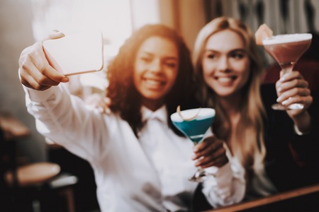 Selfie. Girls. Order. Cocktails. Sit. Bar. Group of Young People. Rest. Drink Alcoholic Beverages. Have Fun. Together. Joyful. Chin-chin. Leisure Time. Nightlife. Positive. Emotion. Clubbing. Guys.の写真素材