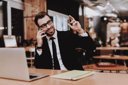 Ideas. Business Suit. Talking on Phone. Project. Laptop. Sit. Brainstorm. Young Guy. Businessman. Work. Office. Creative Worker. Businesspeople. Workplace. Inspiration. Comfortable Office. Eyeglasses.の写真素材