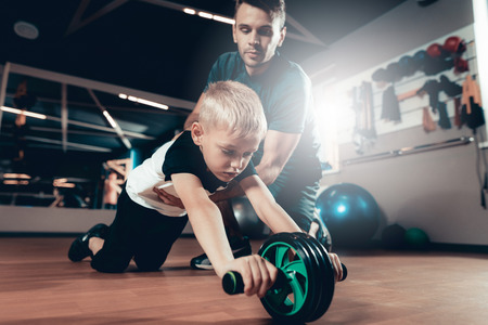 Sporty Child Is Doing Exercises With The Gym Wheel. Parenthood Relationship. Sporty Family Concept. Active Lifestyle. Press Exercise. Holiday Leisure. Working Out Together. Fitness Day.の写真素材