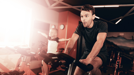Father And Son Are Training On Bike Trail In The Gym. Parenthood Relationship. Sporty Family Concept. Active Lifestyle. Happy Childhood. Holiday Leisure. Working Out Together. Fitness Day.の写真素材