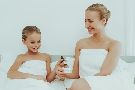Young Mother With Daughter Are Resting. Spa Concept. Relaxing Together. Holiday Leisure. Doing A Make Up. Time To Chill Out. White Body Towels. Smiling Family Weekend. Soft Pillows.の写真素材