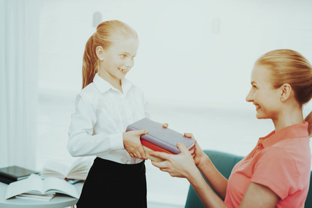 Young Mother Is Prepairing A Daughter For School. Studying Uniform. Black And White Clothes. Button Up. Proud Mum. Clean Dress. Ready To Learn. Family Relationship. Happy Smiling Kid.の写真素材