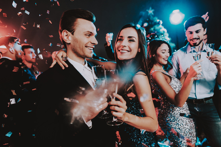 Happy Young People Dancing on New Year Party. Happy New Year Concept. Glass of Champagne. Celebrating of New Year. Young Woman in Dress. Young Man in Suit. Happy People. Modern Dances.の写真素材