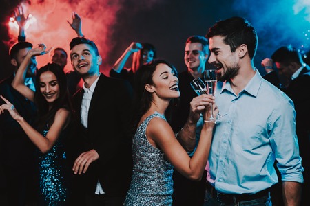 Happy Young People Dancing on New Year Party. Happy New Year Concept. Glass of Champagne. Celebrating of New Year. Young Woman in Dress. Young Man in Suit. Happy People. Modern Dances.の写真素材
