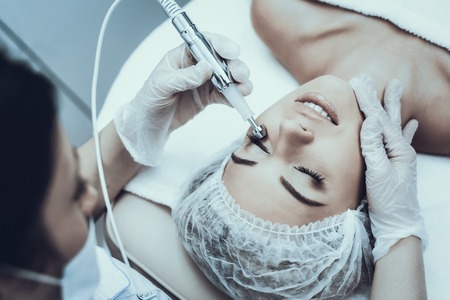 Young Woman in Spa Salon for Laser Hair Removal. Girl in Beauty Salon. Modern Cosmetology. Proffesional Cosmetologist. Doctor with Laser Epilator. Women's Beauty Concept. Medical Equipment.の写真素材
