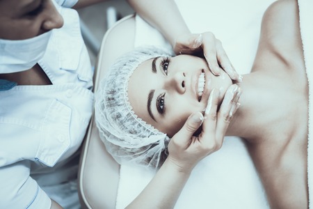 Young Woman in Spa Salon for Cleansing Massage. Girl in Beauty Salon. Modern Cosmetology. Proffesional Cosmetologist. Doctor in White Coat. Women's Beauty Concept. Skin Care and Cleaning.の写真素材