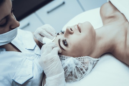 Young Woman in Spa Salon for Cleansing Massage. Girl in Beauty Salon. Modern Cosmetology. Proffesional Cosmetologist. Doctor in White Coat. Women's Beauty Concept. Skin Care and Cleaning.の写真素材
