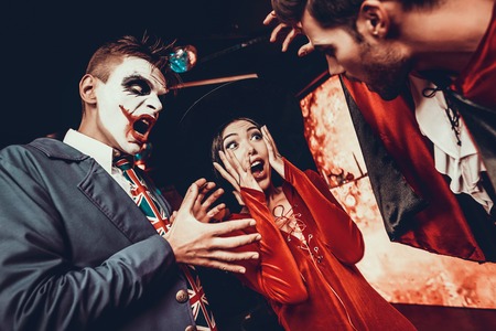 Young People in Costumes Celebrating Halloween. Group of Young Happy Friends Wearing Halloween Costumes having Fun at Party in Nightclub by doing Scary faces. Celebration of Halloweenの写真素材