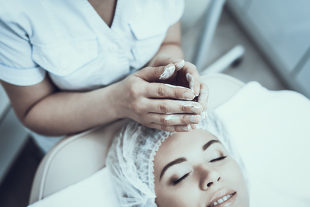 Young Woman in Spa Salon for Cleansing Massage. Girl in Beauty Salon. Modern Cosmetology. Proffesional Cosmetologist. Doctor in White Coat. Women's Beauty Concept. Skin Care and Cleaning.の写真素材