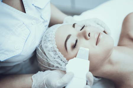 Young Woman in Spa Salon for Laser Hair Removal. Girl in Beauty Salon. Modern Cosmetology. Proffesional Cosmetologist. Doctor with Laser Epilator. Women's Beauty Concept. Medical Equipment.の写真素材