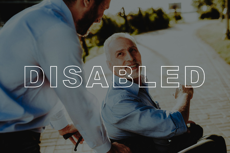 Happily. Sit in Wheelchair. Son and Old Man. Walking in Park. Carry. Happy. Green Bush. Assistance....
