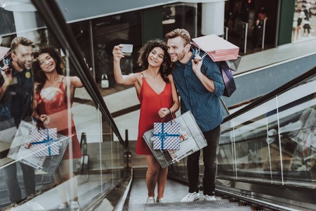 Couple with Packages Taking Selfie on Escalator.の写真素材