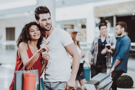 Young Couple with Packages pointing to something in Mall.の写真素材