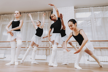 Ballet Training of Group of Young Girls Indoors. Classical Ballet. Girl in Balerina Tutu. Training Indoor. Cute Dancers. Performance in Hall. Dancing Practice. Girls in White Dresses.の写真素材