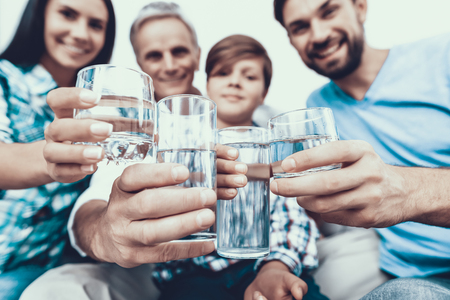 Smiling Family Drinking Water in Glasses at Home. Father and Son. Smiling People. Parenthood Concept. Family at Home. Happy Family. Glass of Water. Young Woman. Family in Dining Room.