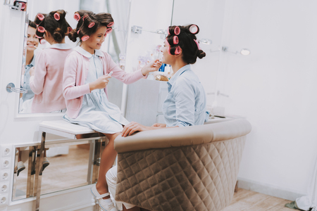 Little Lady with Curlers. Girl with Lipstick. Girl in Beauty Salon. Lipstick in Hands. Consept Beauty Salon. Beautiful Little Lady. Colour Lips. Play with Brushes. Girl and Woman. Beautiful Woman.の写真素材