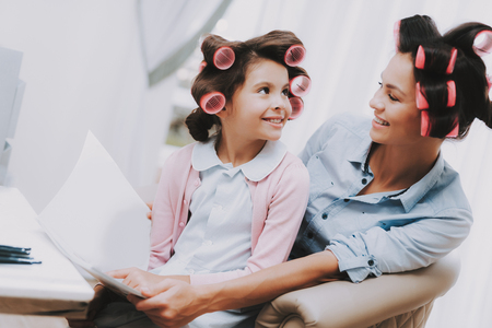 Little Lady with Curlers. Girl in Beauty Salon. Magazine in Hands. Consept Beauty Salon. Beautiful Little Lady. Girl and Woman. Look Each Other. Service Consept. Woman with Curlers. Smiling Person.の写真素材