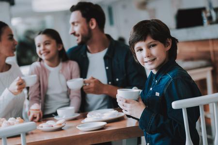 Happy Boy with Cup. Drink Tea. Cupcake. Tea. Celebration. Eat Cakes. Happy Together. Young Family. Mom. Dad and Daughter. Flowers Bouquet. Gifts for Mother. Good Relationship. Family Holiday. Weekend.の写真素材