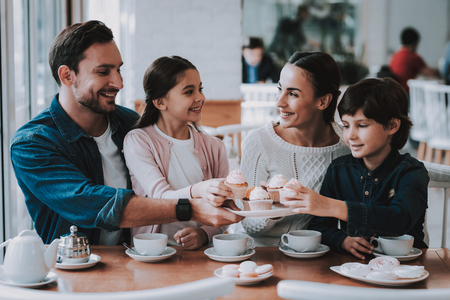 Drink Tea. Cupcake. Tea. Celebration. Eat Cakes. Happy Together. Young Family. Mom. Dad and Daughter. Flowers Bouquet. Gifts for Mother. Good Relationship. Family Holiday. Weekend.の写真素材