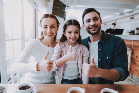 Young Family. Cafe. Happy Together. Good Relationship. Family Holiday. Tea Time. Mom. Dad and Daughter. Active Leisure Time. Cute Relationship. Celebration. Smiling People. Cupcake. Yummy.の写真素材