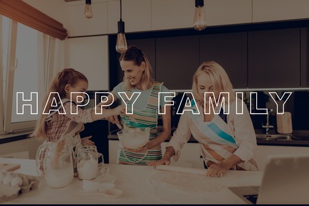 Happy Family. Laptop. Aprons. Smile. Grandmother. Girl Knead Dough. Kitchen. Home-Made. Preparing Cake. Rolling Pin. Have Fan. Recipes. Thanksgiving Day. Together at Home. Celebrating Holiday.の写真素材