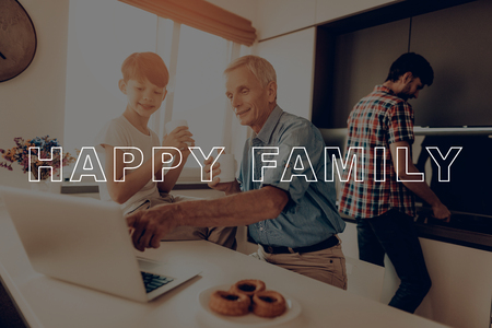 Man. Washes the Dishes. Laptop. Little Son. Cups of Tea. Happy Family. Thanksgiving Day. Traditional Dinner. Son and Father. Have Fan. Together at Home. Autumn Feast. Celebrating Holiday.の写真素材