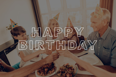 Grandfather. Grandmother. Happy Family. Cheerful. Together at Home. Laughing. Holiday Cap. Congratulate. Holiday. Happy Birthday. Woman. Celebrating. Smiling. Dinner Table. Have Fan. Delicious Food.の写真素材