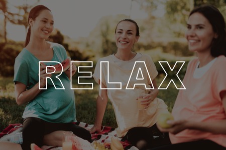 Eat Fruit. Drink. Juice. Glasses. Rug for Picnics. Three Pregnant Women. Happiness. Rest. Smiling. Pregnancy Yoga. Sportswear. Park. Bodycare. Girls. Belly. Have Fun. Mom. Parenthood. Happy Together.の写真素材