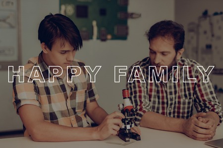 Young Guy Adjusts The Microscope. Father Control. Happy Family Relationship.の写真素材