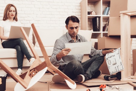 Reading Furniture Instructions. Assemble Furniture. Man Repairing Chair. Man Collects Chair. Furniture Assembler with Drill. Woman on Sofa with Laptop. Folds New Furniture. Master Repair.の写真素材