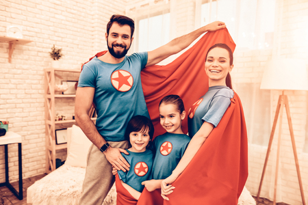 Portrait of Cute Smiling Super Hero Family at Home. Smiling Parents with Children Sitting on Sofa at Home.