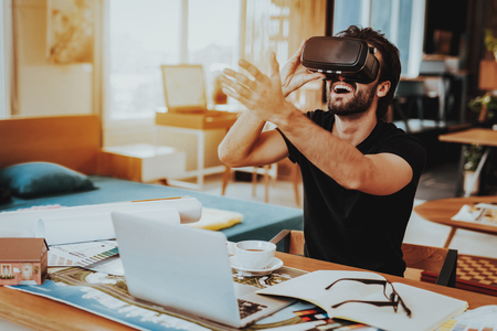 Happy Freelancer Working Remotely and Testing VR. Portrait of Cheerful Caucasian Guy Wears Virtual Reality Gogglesの写真素材