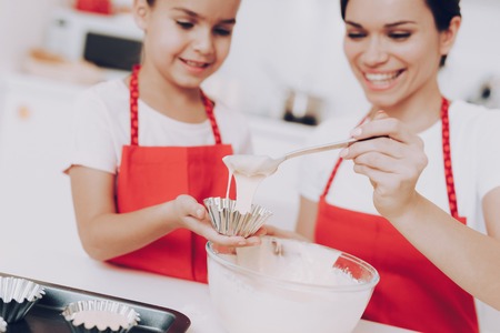 Beautiful Mother and Young Daughter Fill a Form Dough for Biscuit. Dessert for Mom and Girl. Good Day for Mother and Daughter. Kitchen with Mom and Daughter. Happy Time with Mom. Girl with Mom Cook.の写真素材