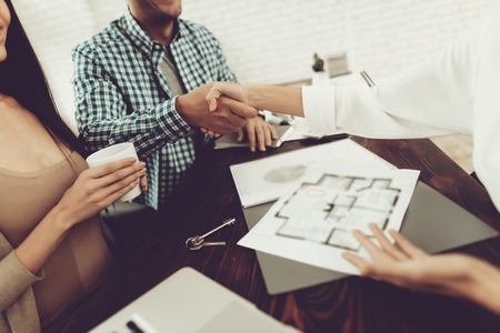 Real Estate Agency. Young Couple. House Sale. Rooms Schemes. Building Planning. End Of A Deal. Happy Family. Business Meeting. Professional Specialist. Bright Office. Handshake With Manager.の写真素材